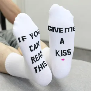 Close-up of white funny socks with 'If you can read this give me a kiss' text on soles
