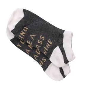 Detailed macro view of gray and white cotton ankle socks featuring knitted 'Badass' quote