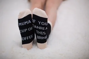 Detailed macro view of funny English letter print on the sole of black cotton crew socks.