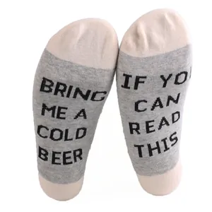 Detailed close-up of novelty gray cotton ankle socks with knitted 'Bring Me a Cold Beer' text