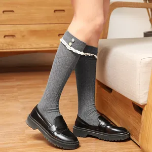 Gros plan de chaussettes hautes grises en tricot avec dentelle blanche et boutons
