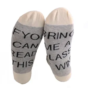 Close-up detail of novelty grey cotton socks with humorous Bring Me A Glass of Wine text