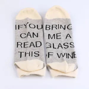 Close-up detail of grey and cream ankle socks featuring funny knitted wine quote on soles.