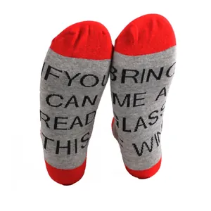 Macro view of grey and red funny socks featuring 'Bring me a glass of wine' knitted text
