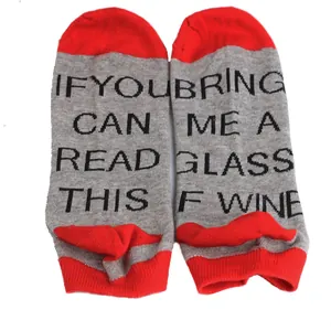Macro view of grey and red novelty ankle socks with 'Bring me wine' text printed on soles