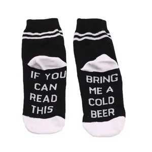 Close-up of novelty cotton crew socks with 'Bring me a cold beer' message on the soles