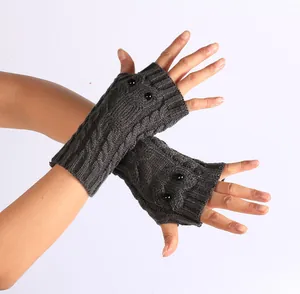 Detail van donkergrijze gebreide vingerloze uilhandschoenen met zwarte kraaloogjes.