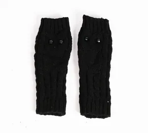 Detail van zwart gebreide vingerloze handschoenen met een schattig uilontwerp en kraaloogjes