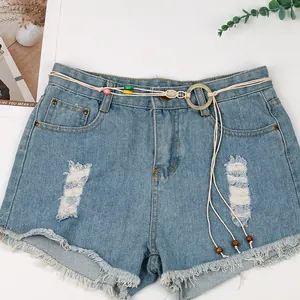 Detail view of handmade bohemian woven belt with colorful beads on blue denim shorts