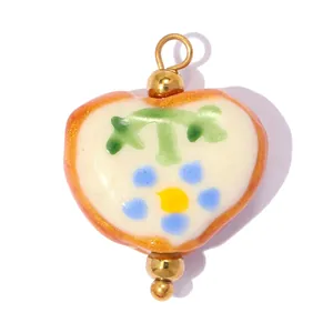 Vue détaillée d'une breloque en céramique en forme de cœur avec motifs floraux peints.