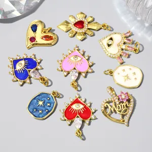 Detail view of 18k gold plated heart and evil eye charms with zircon stones and enamel