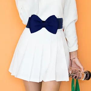 Detail view of a navy blue bow elastic belt styled with a white dress on a model