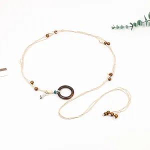 Detailed view of bohemian braided waist chain with wooden ring and shell accents
