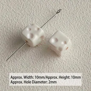 Close-up of small white acrylic cheese-shaped cube beads for DIY crafts