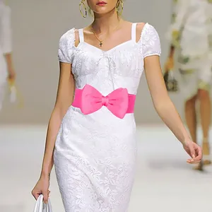 Detailed view of a bright pink elastic waist belt with a large chiffon bow on a dress