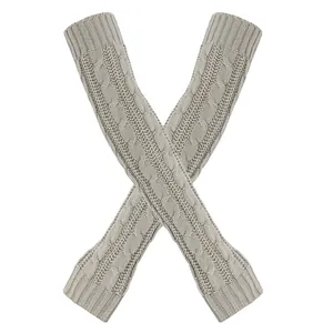Detail van grijze kabelgebreide armwarmers met een warme gevlochten textuur