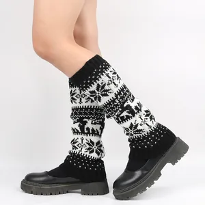 Detailed view of knitted Christmas leg warmers with white snowflake and deer patterns.