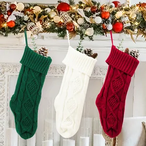 Vue d'ensemble de trois chaussettes de Noël en tricot torsadé sur une cheminée décorée