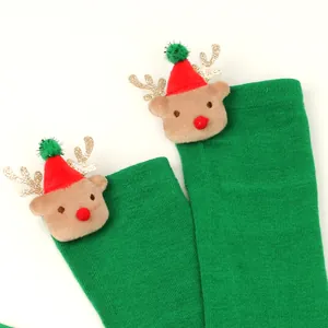 Close-up detail of plush reindeer head decoration on green festive Christmas thigh-high socks.
