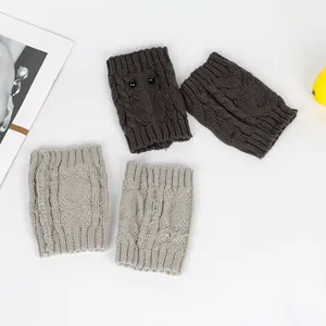 Close-up detail of knitted owl leg warmers with textured cable stitch and bead eyes