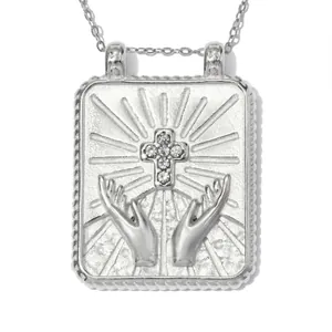 Nahaufnahme eines silbernen Edelstahlanhängers mit Kristallkreuz und Händen gestaltet