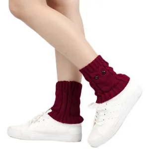 Close-up of burgundy knitted owl leg warmers with eye buttons and white sneakers