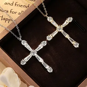 Vue détaillée de deux colliers en croix en moissanite en argent et or dans un écrin.