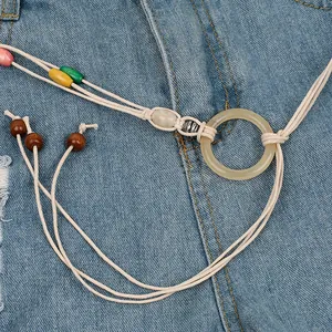 Close-up of a bohemian handmade woven belt with colorful wooden beads and a resin ring