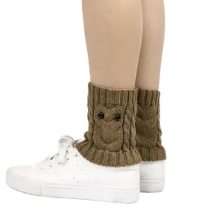 Detail of brown knitted leg warmers with owl pattern and black bead eyes on sneakers