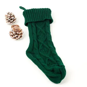 Détail d'une grande chaussette de Noël en tricot vert foncé avec pommes de pin décoratives