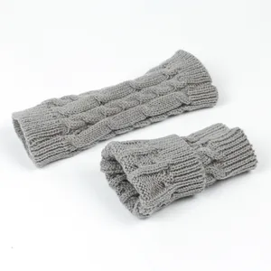 Close-up detail of grey cable knit fingerless gloves showing ribbed cuffs and texture