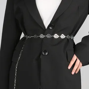 Dettaglio di una catena in metallo argentato con foglie su una giacca blazer nera elegante