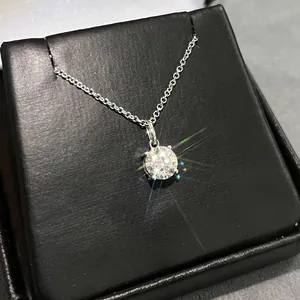 Macro view of a brilliant round cut moissanite solitaire pendant necklace on a black box