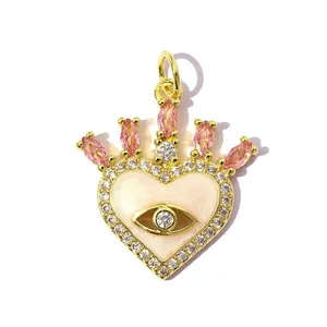 Close-up of a heart-shaped evil eye pendant with pink zircon crown detail and gold plating.