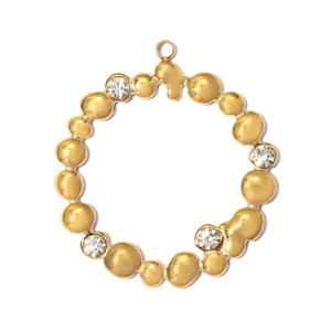Detailed view of a gold stainless steel circular pendant with embossed texture and rhinestones