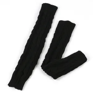 Detailopname van dikke zwarte kabelgebreide armwarmers met warme wintertextuur