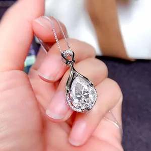 Primo piano della collana con ciondolo in moissanite a goccia tenuta in mano con cura