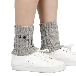 Detailed view of gray cable-knit owl pattern leg warmers worn over white sneakers