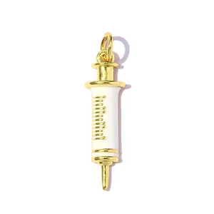 Detailed macro view of a gold and white enamel syringe-shaped jewelry charm pendant