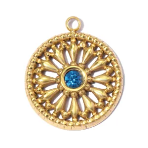 Detailed macro view of a gold-tone sunburst pendant with a sparkling blue gemstone