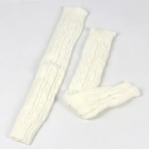 Detail van crème kabelgebreide lange armwarmers met dikke gevlochten textuur