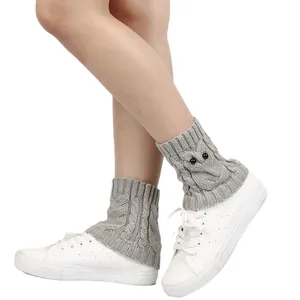 Macro detail shot of grey knitted owl boot cuffs with beads worn over white sneakers