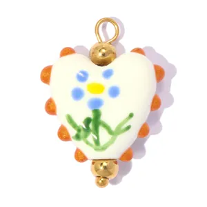 Gros plan d'un pendentif en céramique en forme de cœur avec une fleur bleue peinte