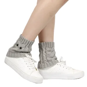 Detail view of grey knitted owl leg warmers with decorative eye buttons and cable patterns