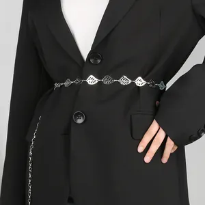 Dettaglio ravvicinato di una catena da vita in metallo argentato con foglie su blazer nero.
