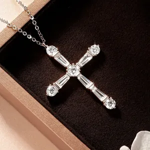 Élégant collier croix géométrique avec pierres moissanites étincelantes dans une boîte.