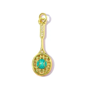 Macro view of gold-plated tennis racket pendant with green ball and cubic zirconia