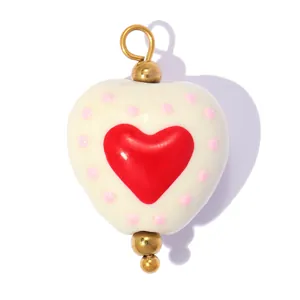 Vue détaillée d'un pendentif cœur en céramique blanc avec points roses et cœur rouge DIY