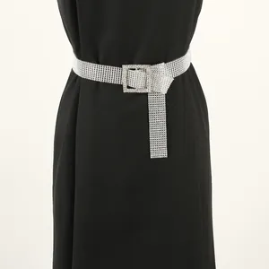 Close-up of shimmering silver rhinestone belt with square buckle on elegant black dress