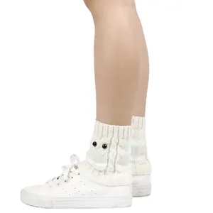 Detail view of white cable knit owl boot cuffs featuring decorative black button eyes